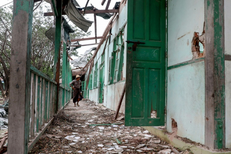 Un homme regarde à l'intérieur d'un bâtiment scolaire endommagé lors d'un bombardementde l'armée birmane dans le village d'Ohe Htein, dans la région de Sagaing, le 12 mai 2025 en Birmanie ( AFP / - )