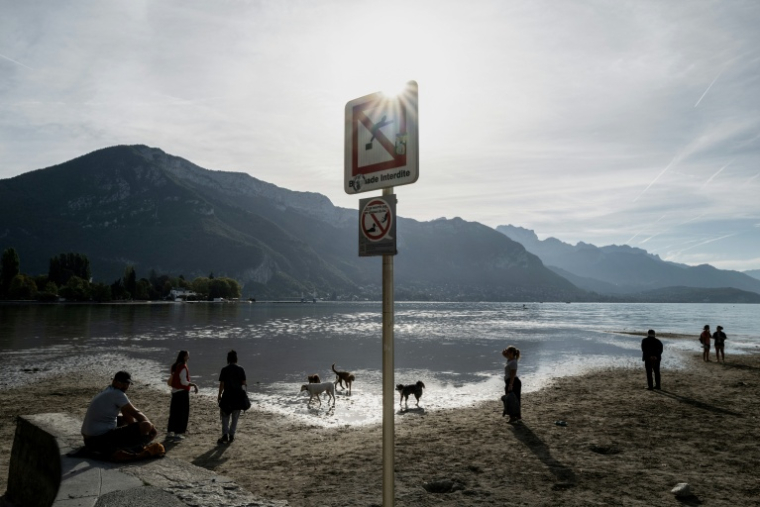 Des promeneurs avec leurs chiens sur les rives du lac d'Annecy, le 24 septembre 2026 ( AFP / Jeff PACHOUD )