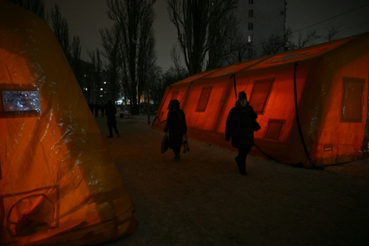 Des habitants passent entre des tentes de secours installées pour les personnes dont les maisons sont privées d'électricité ou de chauffage après des frappes russes contre les infrastructures énergétiques, le 22 janvier 2026 à Kiev, en Ukraine ( AFP / Genya SAVILOV )