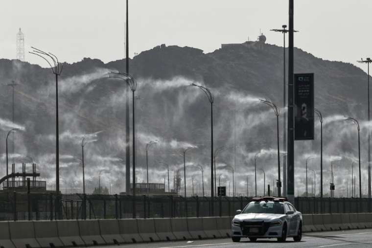 Une voiture de police passe devant des brumisateurs installés à La Mecque, à la veille du pèlerinage annuel du Hajj, le 23 mai 2026 en Arabie saoudite ( AFP / Zain JAAFAR )