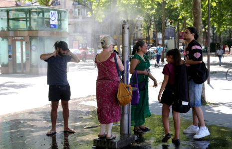 Des passants se rafraîchissent grâce à une fontaine brumisante à Paris, le 21 juin 2025 ( AFP / ROMAIN PERROCHEAU )