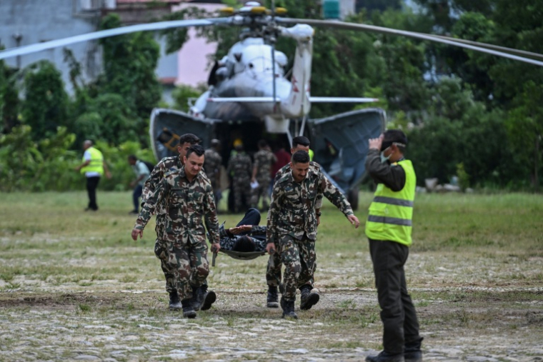 Des militaires transportent un blessé sur une civière lors des opérations de secours après la crue destructrice qui a fait plus de 600 morts à la frontière entre le Népal et la Chine, le 29 août 2026 à Trishuli, dans le district népalais de Nuwakot  ( AFP / Arun SANKAR )