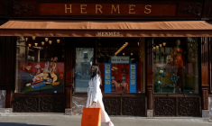 Une femme marche devant un magasin Hermès à Paris