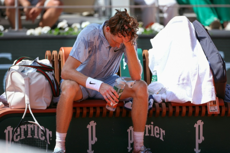 Le N.1 mondial Jannik Sinner tente de se rafraîchir sous une chaleur accablante, lors de son match finalement perdu face à l'Argentin Manuel Cerundolo, le 28 mai 2026 à Roland-Garros ( AFP / ALAIN JOCARD )