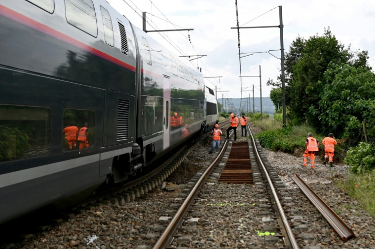 Des employés de la SNCF à pied d'oeuvre à côté d'un TGV de la ligne Toulouse-Bordeaux qui a dû s'arrêter en pleine voie, le ballast sous les rails ayant été emporté sur une dizaine de mètres à la suite de pluies diluviennes, le 20 mai 2025 à Tonneins, dans le Lot-et-Garonne ( AFP / Christophe ARCHAMBAULT )