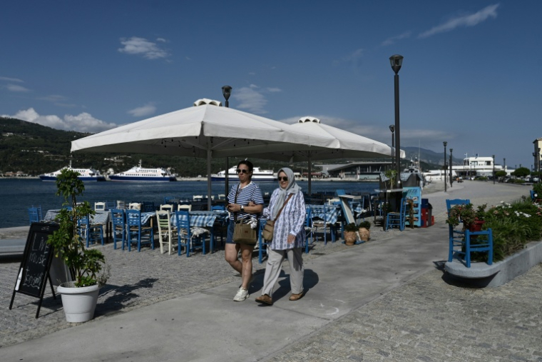 Des touristes venus de Turquie se promènent dans le village de Vathy, sur l’île de Samos, le 25 juillet 2026 ( AFP / Sakis Mitrolidis )