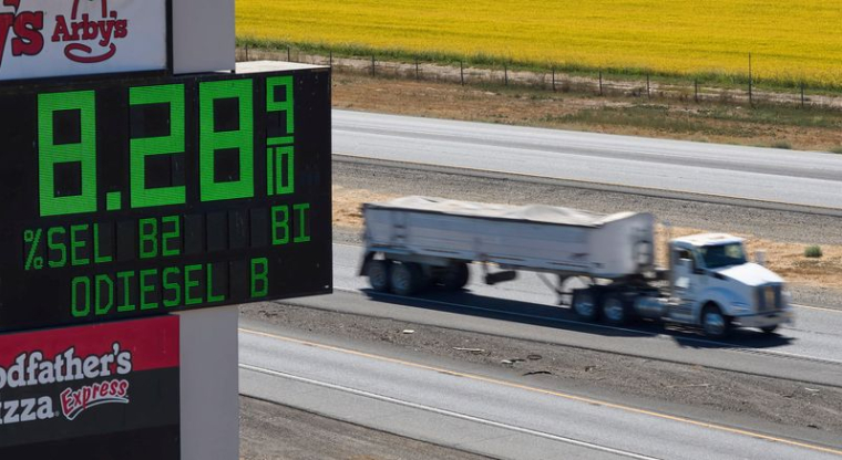 Des poids lourds passent devant un panneau indiquant les prix du carburant