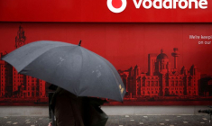 Un homme utilise un parapluie alors qu'il passe devant un magasin de téléphonie mobile Vodafone à Liverpool