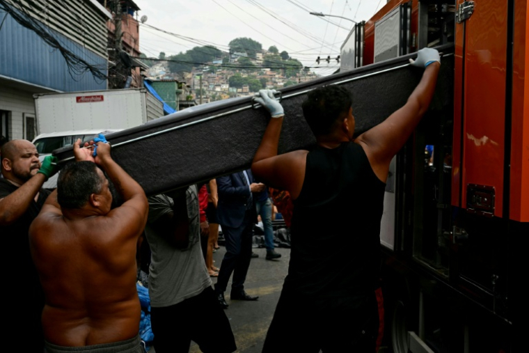 Des habitants hissent un corps dans une des favelas du Complexo da Penha, à Rio de Janeiro, le 29 octobre 2025 ( AFP / Pablo PORCIUNCULA )