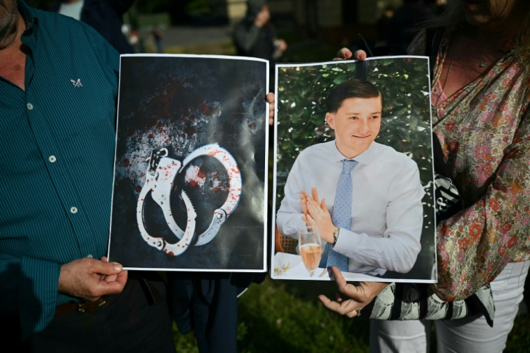 Des manifestants tiennent des photos de la victime Henry Nowak et de menottes ensanglantées lors d'une manifestation devant le commissariat central de Southampton, le 2 juin 2026 dans le sud de l'Angleterre ( AFP / JUSTIN TALLIS )