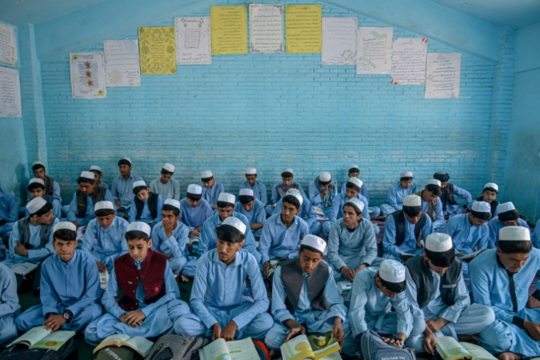 Des élèves en shalwar kameez et chapeaux blancs, selon le nouveau code d'uniforme, le 22 avril 2025 à Kandahar, en Afghnistan ( AFP / Sanaullah SEIAM )