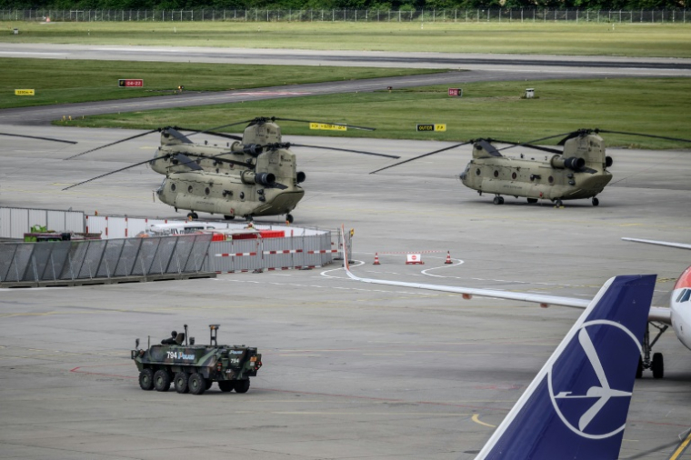 Un véhicule blindé de la police suisse passe devant un hélicoptère de l'armée américaine sur le tarmac de l'aéroport de Genève, le 11 juin 2026  ( AFP / Fabrice COFFRINI )