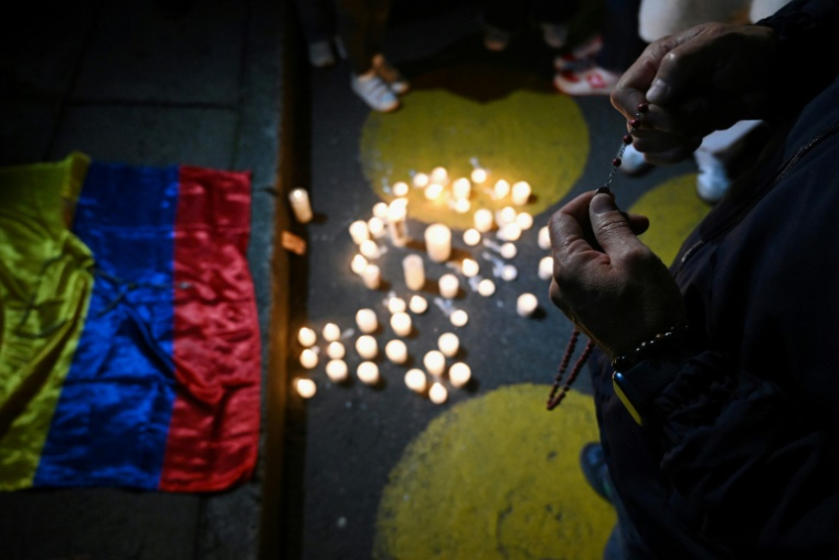 Un homme tient un crucifix pendant qu'il prie devant la clinique où le sénateur Miguel Uribe est hospitalisé après avoir été blessé par balle, à Bogota, le 7 juin 2025 ( AFP / Raul ARBOLEDA )