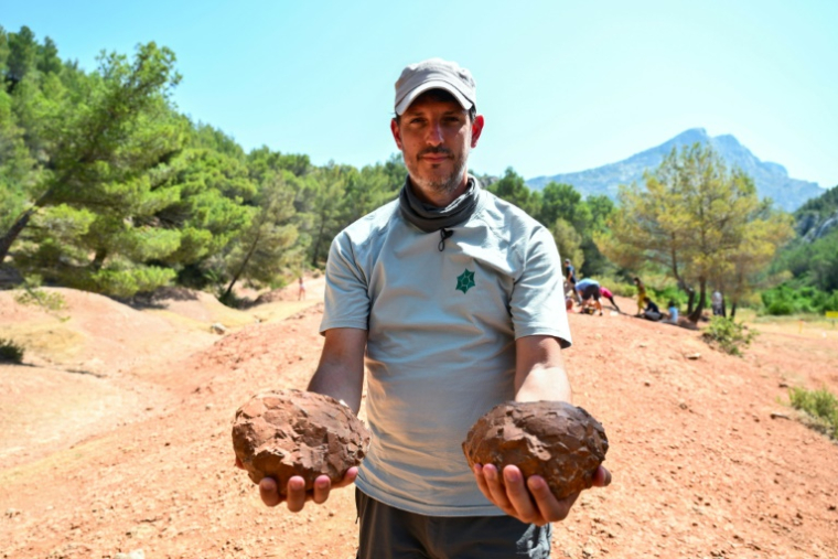 Thierry Tortosa, paléontologue et conservateur de la Réserve Naturelle Nationale de Sainte-Victoire, montre des oeufs de dinosaures trouvés sur le site, le 25 juin 2025 près d'Aix-en-Provence, dans les Bouches-du-Rhône ( AFP / Christophe SIMON )