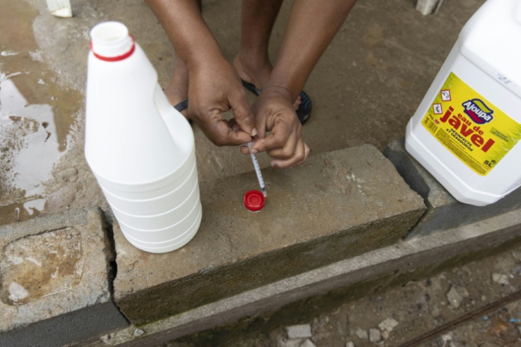 Un conseiller de la Croix-Rouge s'apprête à ajouter une dose d'eau de Javel à de l'eau pour la rendre potable, le 6 juin 2026 à Savane, un quartier de Matoury, en périphérie de Cayenne ( AFP / Ronan LIÉTAR )
