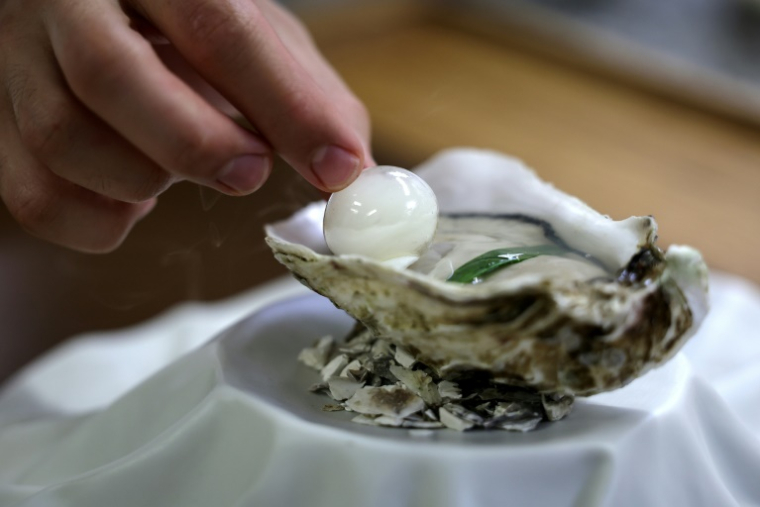 Le chef pâtissier français Axel Goujon pose une perle remplie de fumée de hêtre sur une huître au restaurant "Auberge du Vieux Puits"à Fontjoncouse, dans le sud-ouest de la France, le 25 avril 2025 ( AFP / Valentine CHAPUIS )