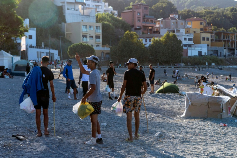 Des migrants restés à Ceuta marchent sur une plage de l'enclave espagnole au Maroc après avoir reçu de la nourriture de la Croix-Rouge, le 22 août 2026 ( AFP / Antonio Sempere )