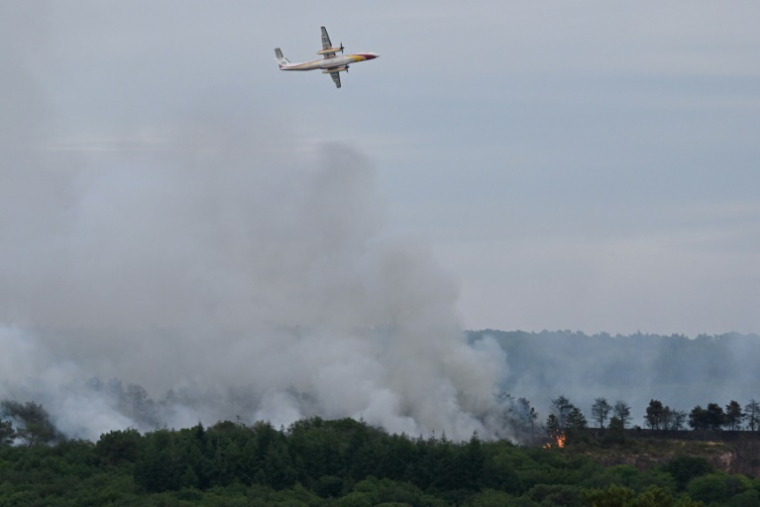 Un bombardier d'eau Dash 8-Q400 MR de la Sécurité civile largue de l'eau au-dessus de la forêt de Brocéliande après qu'un incendie s'est déclaré, le 17 juillet 2025 à Tréhorenteuc, dans le Morbihan ( AFP / Damien MEYER )