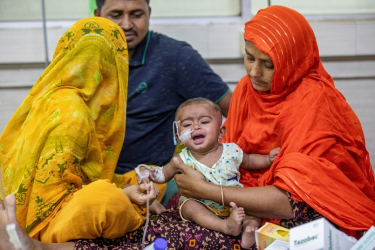Une femme réconforte un enfant atteint de la rougeole à l'hôpital Shishu à Dacca le 6 mai 2026 ( AFP / Salahuddin AHMED )