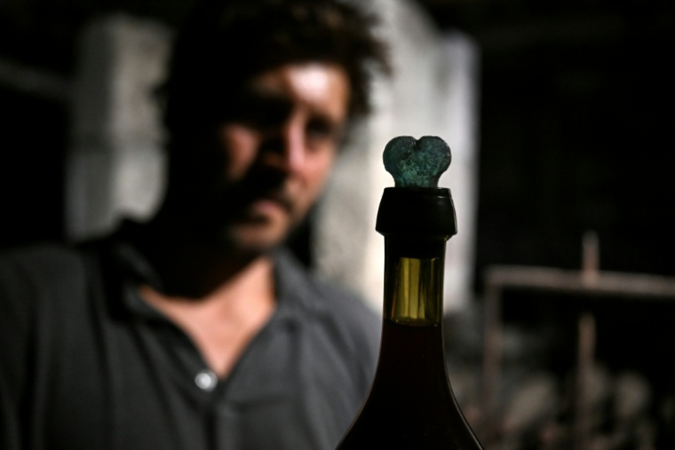 Le directeur et copropriétaire du domaine viticole Château Coutet Adrien David-Beaulieu devant une bouteille retrouvée dans une cave du château datant du XVIIIe siècle, à Saint-Emilion, le 7 septembre 2026 ( AFP / Christophe ARCHAMBAULT )