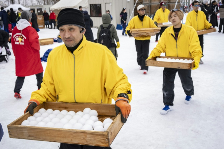 Des joueurs portent des caisses remplies de boules de neige avant une partie de "yukigassen" à Sobetsu, sur l'île septentrionale japonaise d'Hokkaido, le 21 février 2026 ( AFP / Yuichi YAMAZAKI )