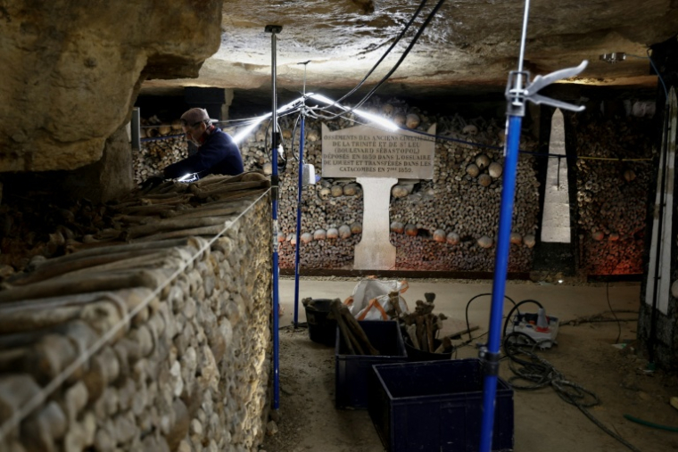 Un ouvrier construit un mur avec des ossements humains lors des travaux de restauration des Catacombes de Paris, le 24 mras 2026 ( AFP / Kenzo TRIBOUILLARD )
