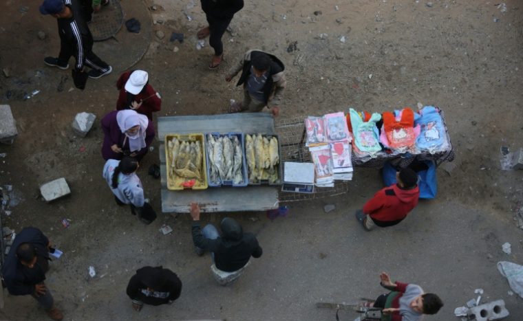 Des Palestiniens regardent du poisson salé vendu sur un marché de rue alors qu'ils se préparent pour l'Aïd el-Fitr, la fête marquant la fin du mois sacré de jeûne musulman du Ramadan, à Khan Younès, dans le sud de la bande de Gaza, le 17 mars 2026 ( AFP / Bashar Taleb )
