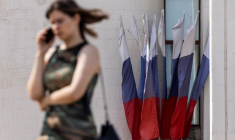 Une femme parle au téléphone en passant devant des drapeaux nationaux russes à Koursk