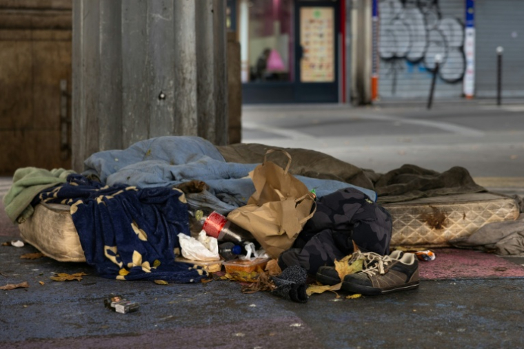 Un sans-abri dort sur un matelas dans une rue de Paris, le 1er décembre 2025 ( AFP / JOEL SAGET )