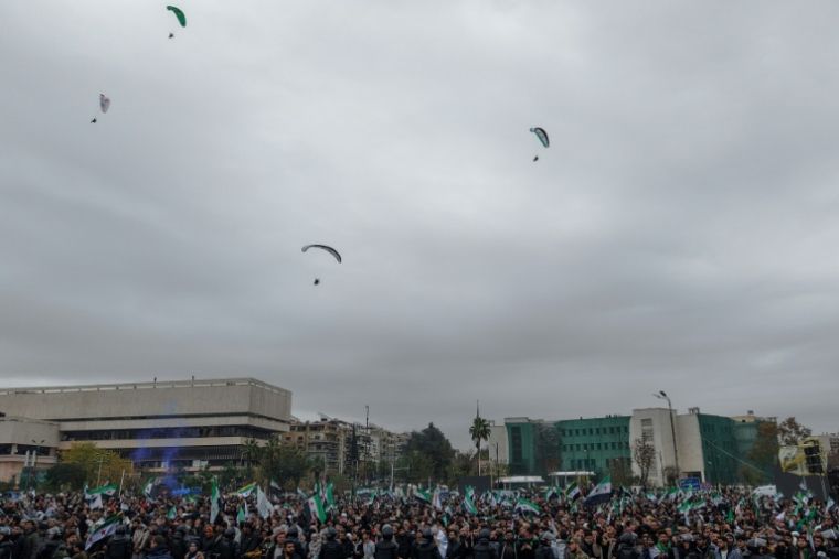 Des parapentistes survolent la place des Omeyyades à Damas, lors du premier anniversaire de la chute de Bachar al-Assad, le 8 décembre 2025 ( AFP / Bakr ALKASEM )