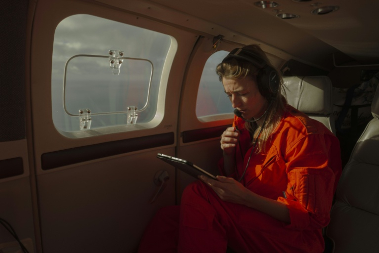 Une membre de l’ONG Initiative pilote humanitaire (HPI) consulte Une carte lors d'une mission de surveillance de la route atlantique entre l’Afrique de l’Ouest et les îles Canaries, pour repérer des embarcations de migrants en difficulté, le 22 janvier 2026 ( AFP / MICHELE CATTANI )