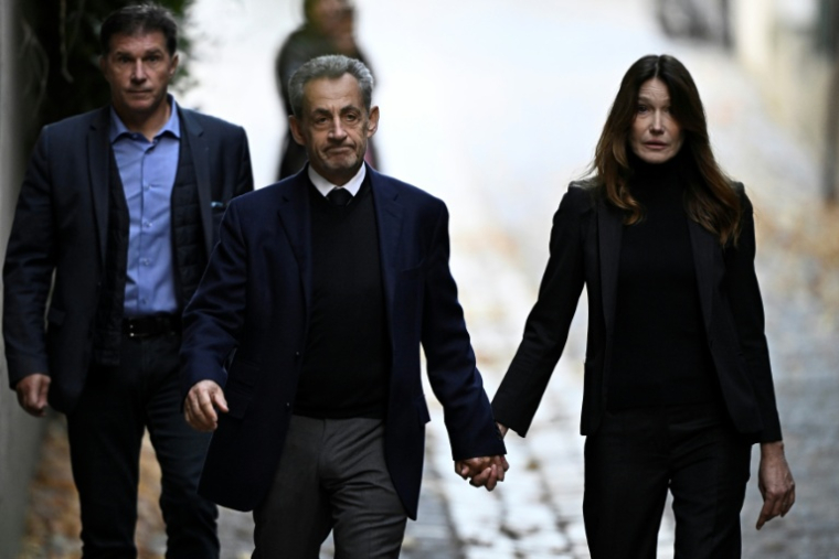 Nicolas Sarkozy (C) et son épouse Carla Bruni-Sarkozy, le jour de son incarcération à la prison de la Santé, le 21 octobre 2025 à Paris ( AFP / JULIEN DE ROSA )