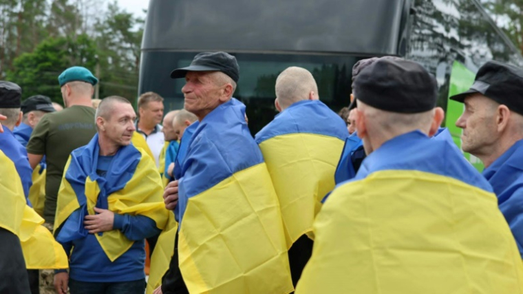 Photo publiée par le quartier général de coordination pour le traitement des prisonniers de guerre, le 20 juin 2025, de prisonniers de guerre ukrainiens enveloppés dans un drapeau national à la suite d'un échange dans un lieu non divulgué en Ukraine ( Quartier général de coordination pour le traitement des prisonniers de guerre / Handout )