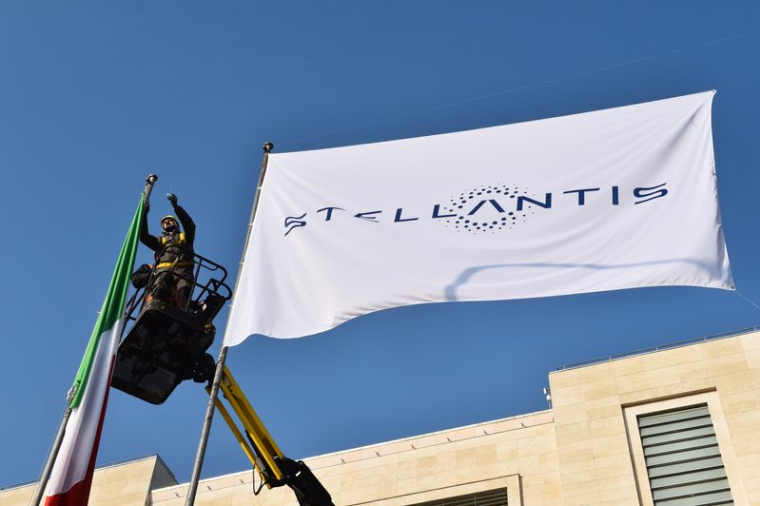 Des ouvriers installent un drapeau avec le logo de Stellantis, à l'entrée principale de l'usine FCA Mirafiori à Turin