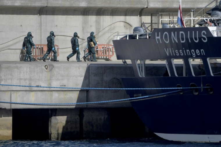 Des personnes en combinaisons de protection se dirigent vers le bateau de croisière MV Hondius, touché par l'hantavirus, dans le port de Granadilla de Abona, sur l'île de Tenerife, dans l'archipel espagnol des Canaries, le 11 mai 2026 ( AFP / JORGE GUERRERO )