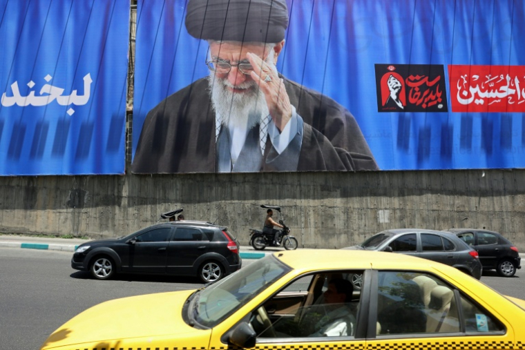Des automobilistes passent devant un panneau géant sur lequel figure une photo de l'ayatollah Ali Khamenei, le défunt guide suprême de l'Iran, le 2 juillet 2026 à Téhéran, à la veille de ses funérailles ( AFP / - )
