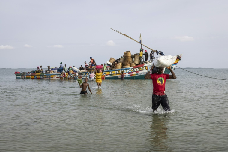 Des habitants de l'île de Nyangai transportent des marchandises déchargées d'une pirogue, le 29 avril 2025 au large de la Sierra Leone ( AFP / PATRICK MEINHARDT )