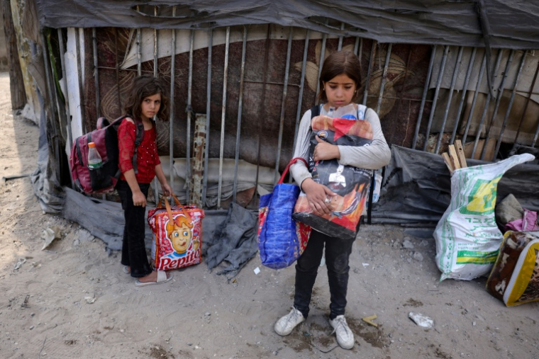 Des fillettes palestiniennes dans l'attente d'évacuer avec leurs familles le quartier Abou Iskandar dans le nord de la ville de Gaza, pilonnée par l'armée israélienne avant une offensive au sol attendue, le 22 août 2025 ( AFP / Bashar TALEB )