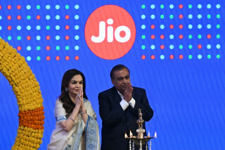 Le milliardaire indien et président de Reliance Industries, Mukesh Ambani (d), et son épouse Nita Ambani, saluent l'assistance lors de l'introduction en bourse de Jio Platforms à la Bourse de Bombay, le 28 octobre 2026 en Inde ( AFP / Indranil MUKHERJEE )