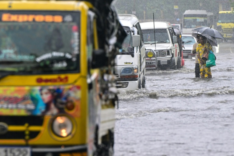 Des personnes pataugent dans une route inondée à Biyagama, en périphérie de Colombo, le 28 novembre 2025 ( AFP / Ishara S. KODIKARA )