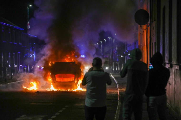 Un véhicule incendié lors d'une manifestation anti-immigration à Ballymena, après l'arrestation de deux adolescents roumanophones accusés d'avoir tenté de violer une jeune fille, le 10 juin 2025 en Irlande du Nord ( AFP / PAUL FAITH )