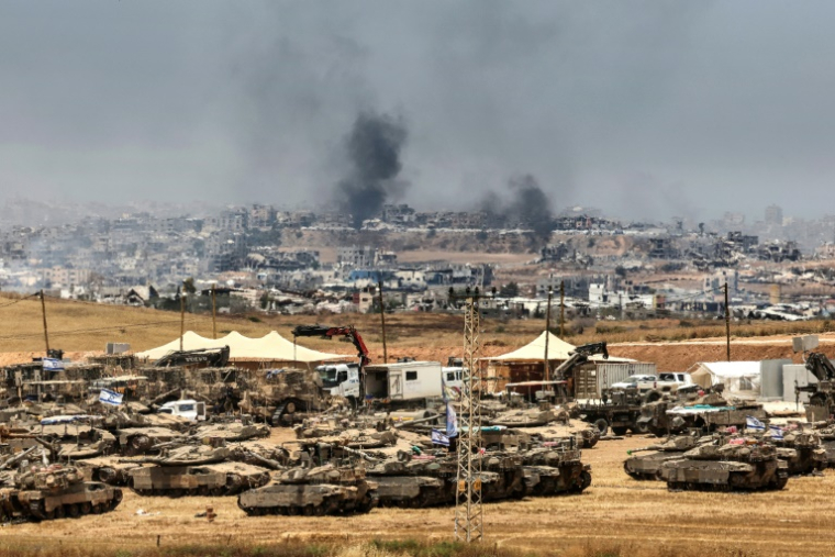 Des tanks et des bulldozers israéliens déployés à la lisière de la bande de Gaza, d'où s'élève de la fumée de bâtiments détruits par des frappes israéliennes, le 17 mai 2025 ( AFP / Jack GUEZ )