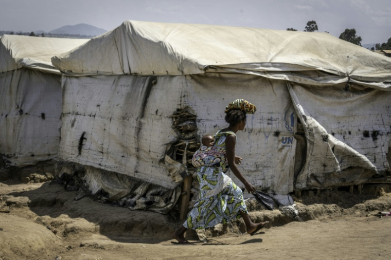 Une femme déplacée, son enfant sur le dos, traverse le camp de Kigonze à Bunia, dans l'est de la République démocratique du Congo, le 28 mai 2026 alors qu'une épidémie d'Ebola touche le pays ( AFP / Glody MURHABAZI )