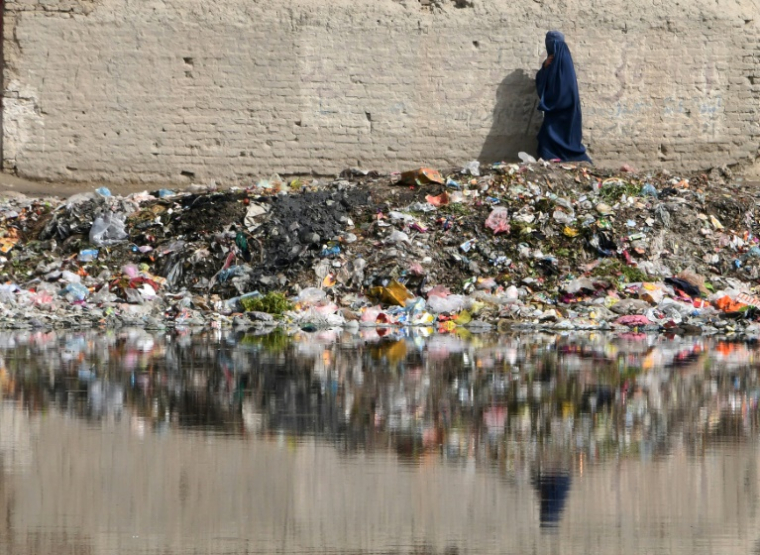 Une femme marche à côté de déchets, notamment plastique, le 6 mai 2018 à Kaboul ( AFP / DOMINIQUE FAGET )