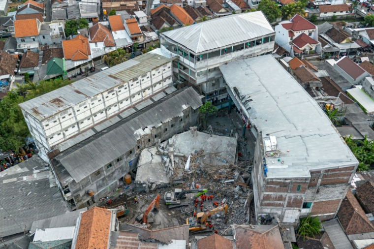 Vue aérienne des sauveteurs à la recherche de victimes à l'école islamique Al Khoziny à Sidoarjo, dans la province de Java oriental, après l'effondrement d'un bâtiment pendant les prières, le 5 octobre 2025 en Indonésie ( AFP / Dicky Bisinglasi )