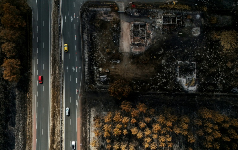 Des voitures circulent sur une route jouxtant des propriétés incendiées, à la suite d'un feu de forêt qui a fait rage en Gironde, à Lanton, le 4 août 2026 ( AFP / Christophe ARCHAMBAULT )