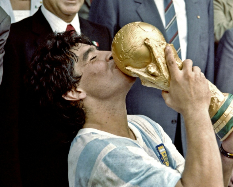 Sur cette photo prise le 29 juin 1986, la star du football argentin et capitaine de l'équipe, Diego Maradona, embrasse la Coupe du monde remportée par son équipe après une victoire 3-2 contre l'Allemagne de l'Ouest au stade Azteca à Mexico ( AFP / Dominique FAGET )