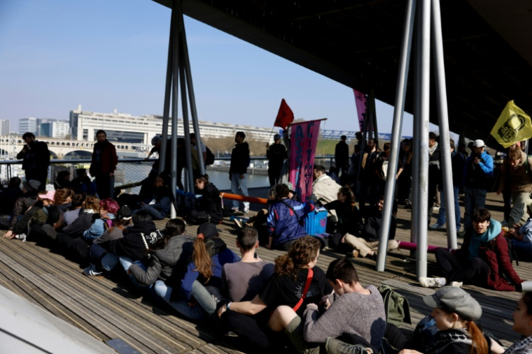 Des militants du groupe écologiste Extinction Rebellion (XR) occupent la passerelle Simone-de-Beauvoir dans Paris, le 21 mars 2026 ( AFP / Kenzo TRIBOUILLARD )
