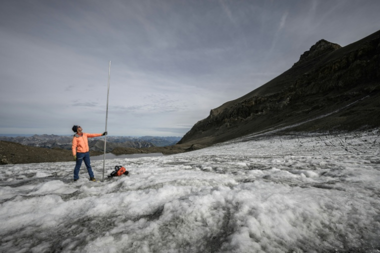 Le glaciologue Matthias Huss brandit une perche de mesure de quatre mètres de long, équivalant à la hauteur de la couche de glace ayant fondu en un an, le 24 septembre 2024 sur le glacier du Scex Rouge, en Suisse ( AFP / Fabrice COFFRINI )