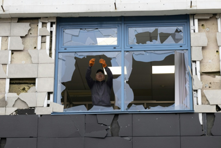 Un homme observe une vitre brisée dans un immeuble de bureaux endommagé à la suite d'une frappe aérienne à Kiev, le 22 octobre 2026. ( AFP / Serhii Okunev )